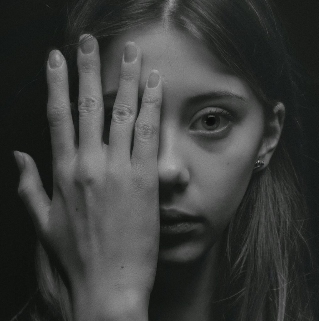 A striking black and white portrait of a young woman with a contemplative expression, shot in a studio.